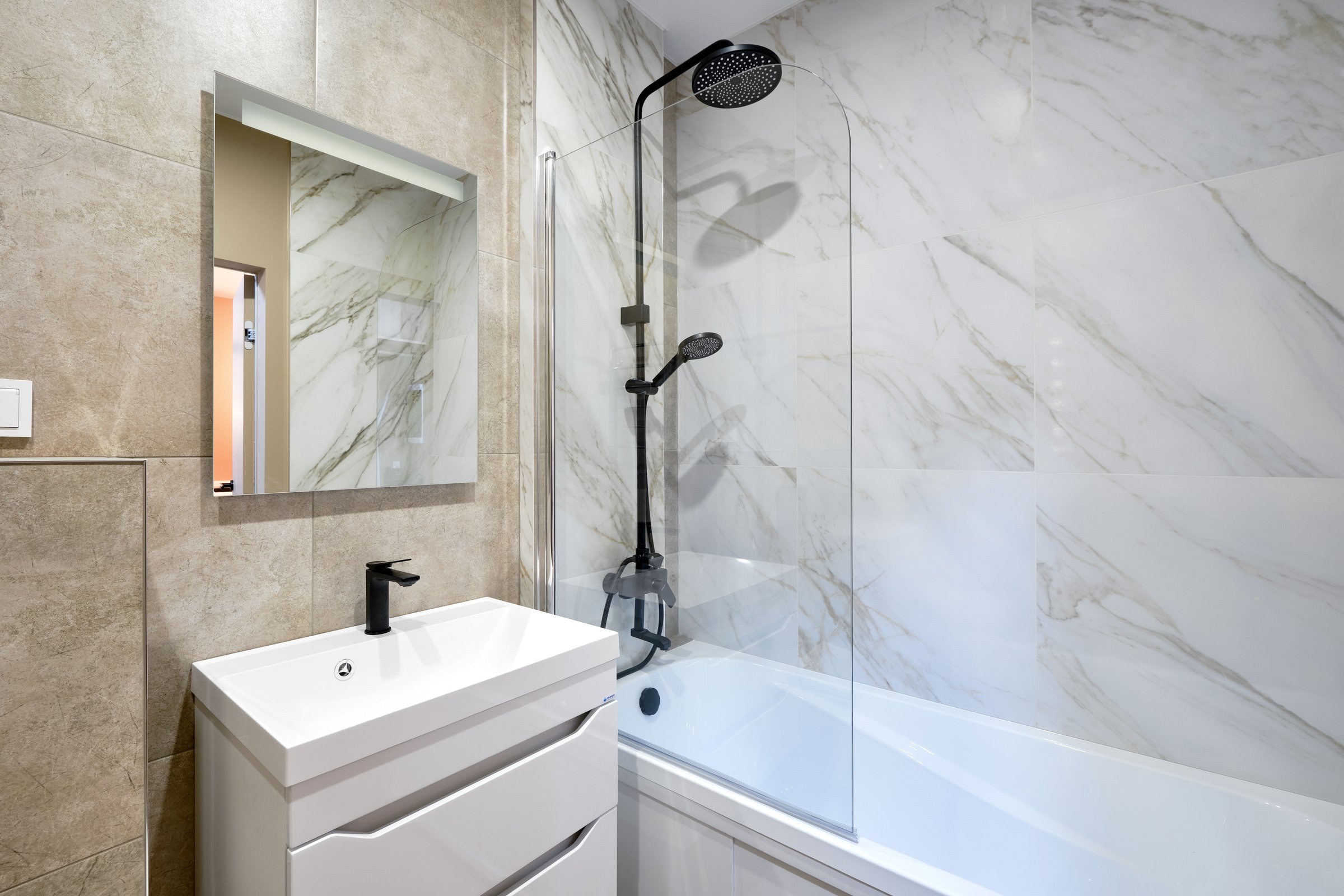 Bathroom lined in white marble with a black shower set