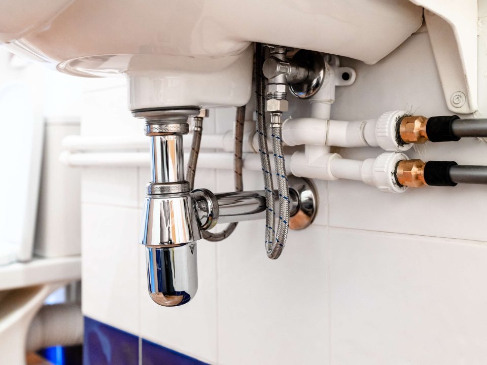 Chrome waste pipes under a household sink