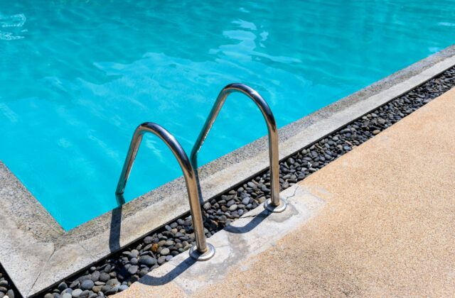 Swimming pool with a stainless ladder on a sunny day