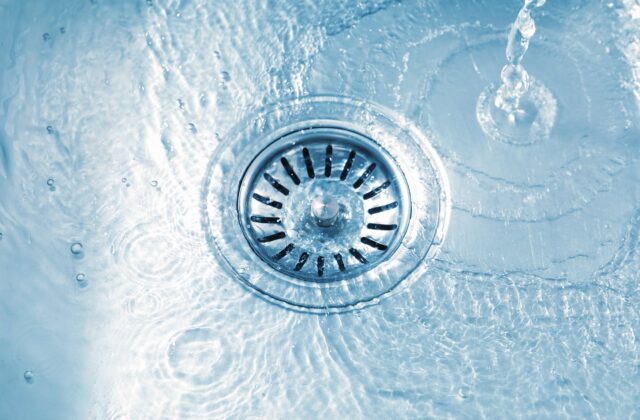 Water running into a stainless sink drain