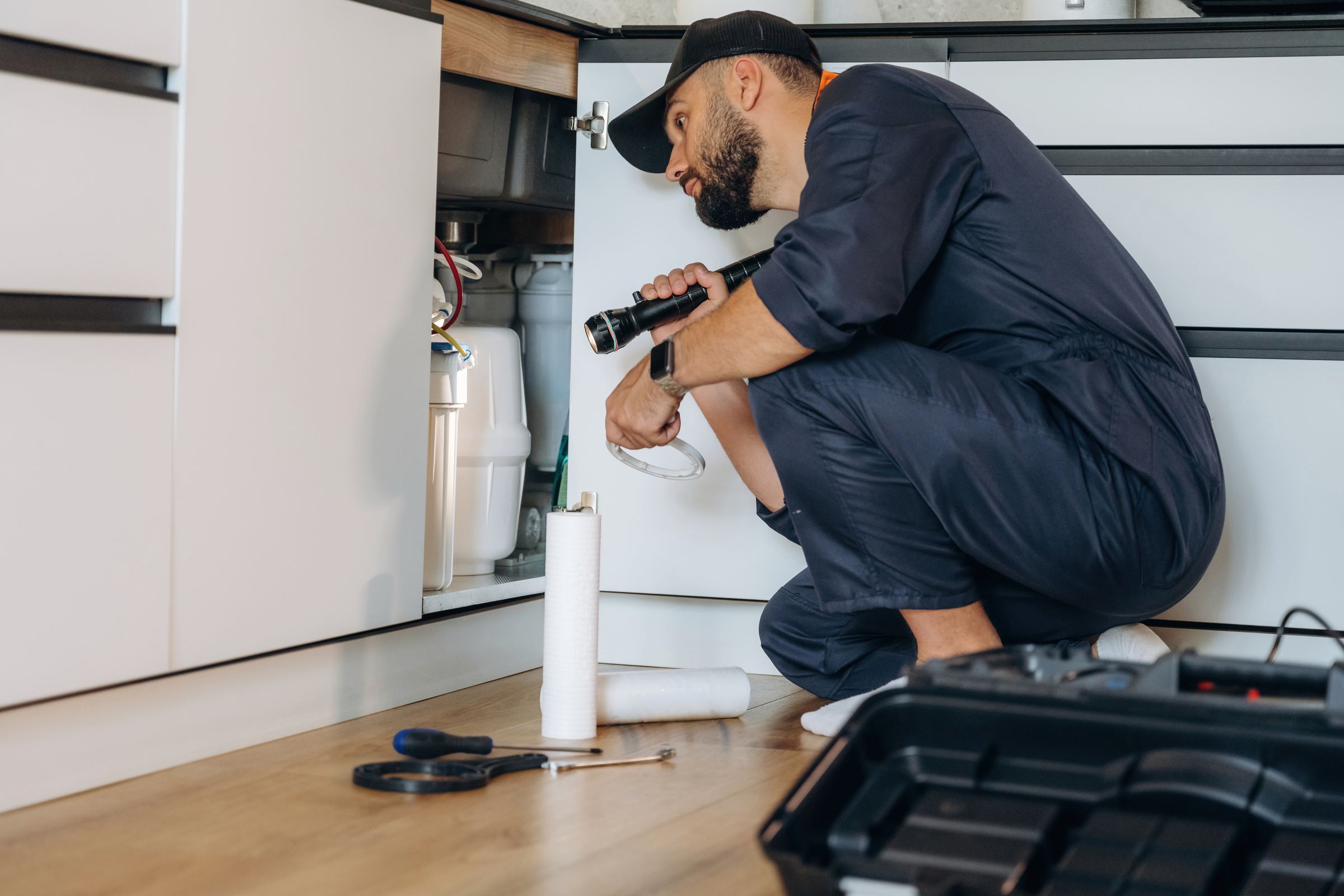 Plumber repairing a sink in a modern home
