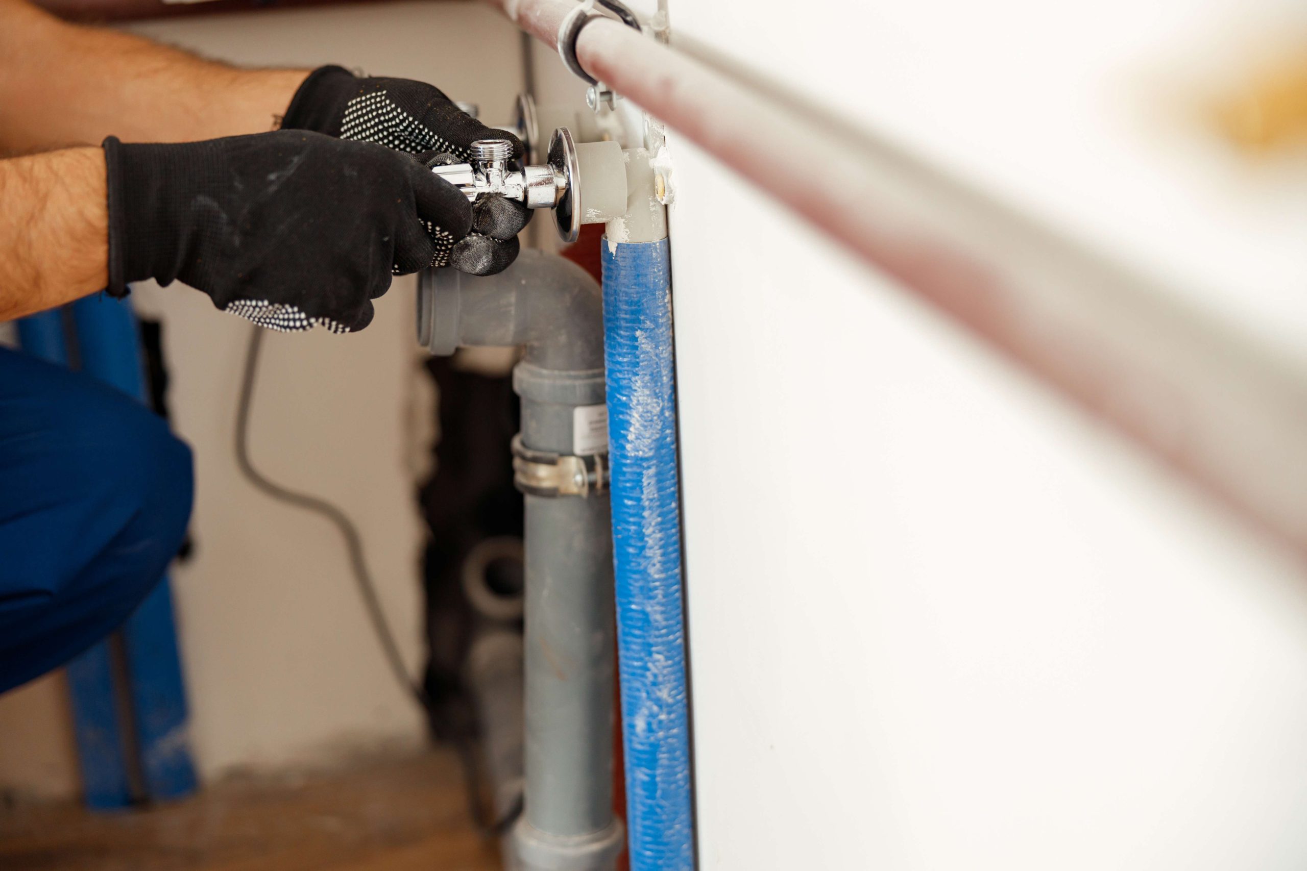 Plumber repairing a pipe under a kitchen cabinet